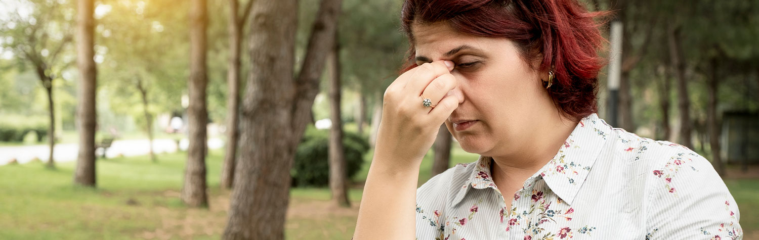 A woman holding her nose in allergy pain
