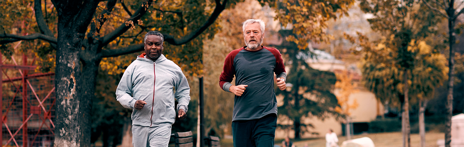 Two older men running on an outdoor trail.