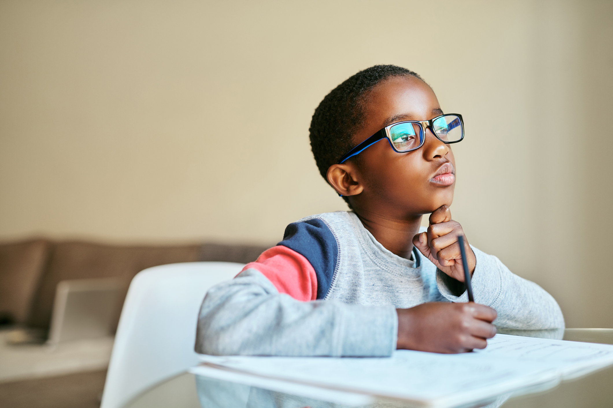 A shot of a child in glasses doing their schoolwork