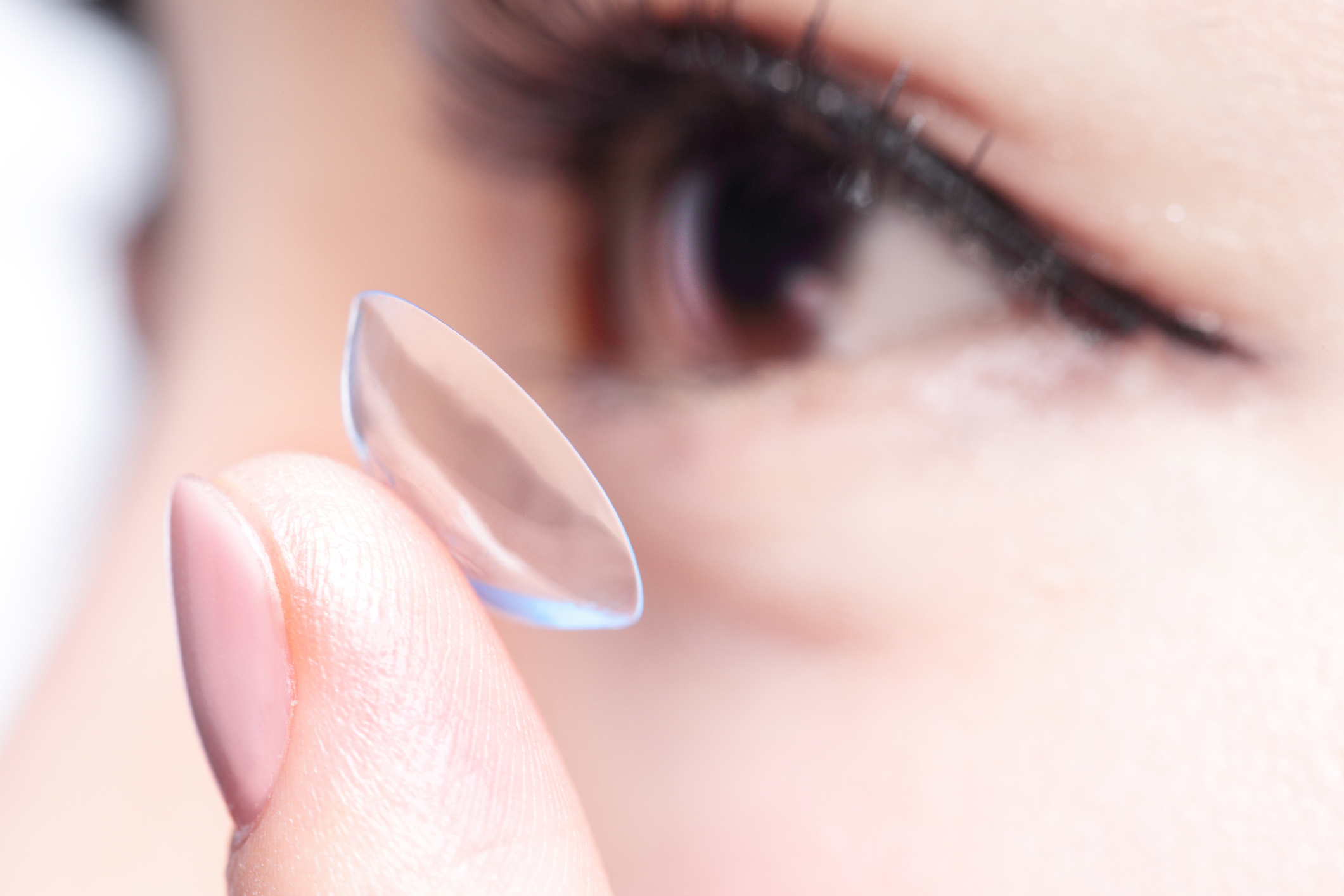 Close up of a woman preparing to apply a contact lens.