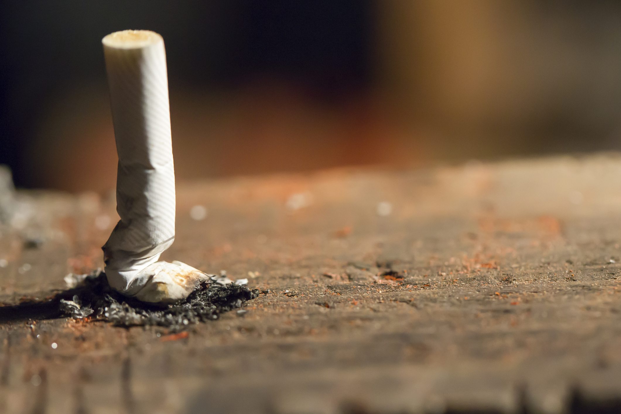 A stubbed out cigarette on a dirty brick.