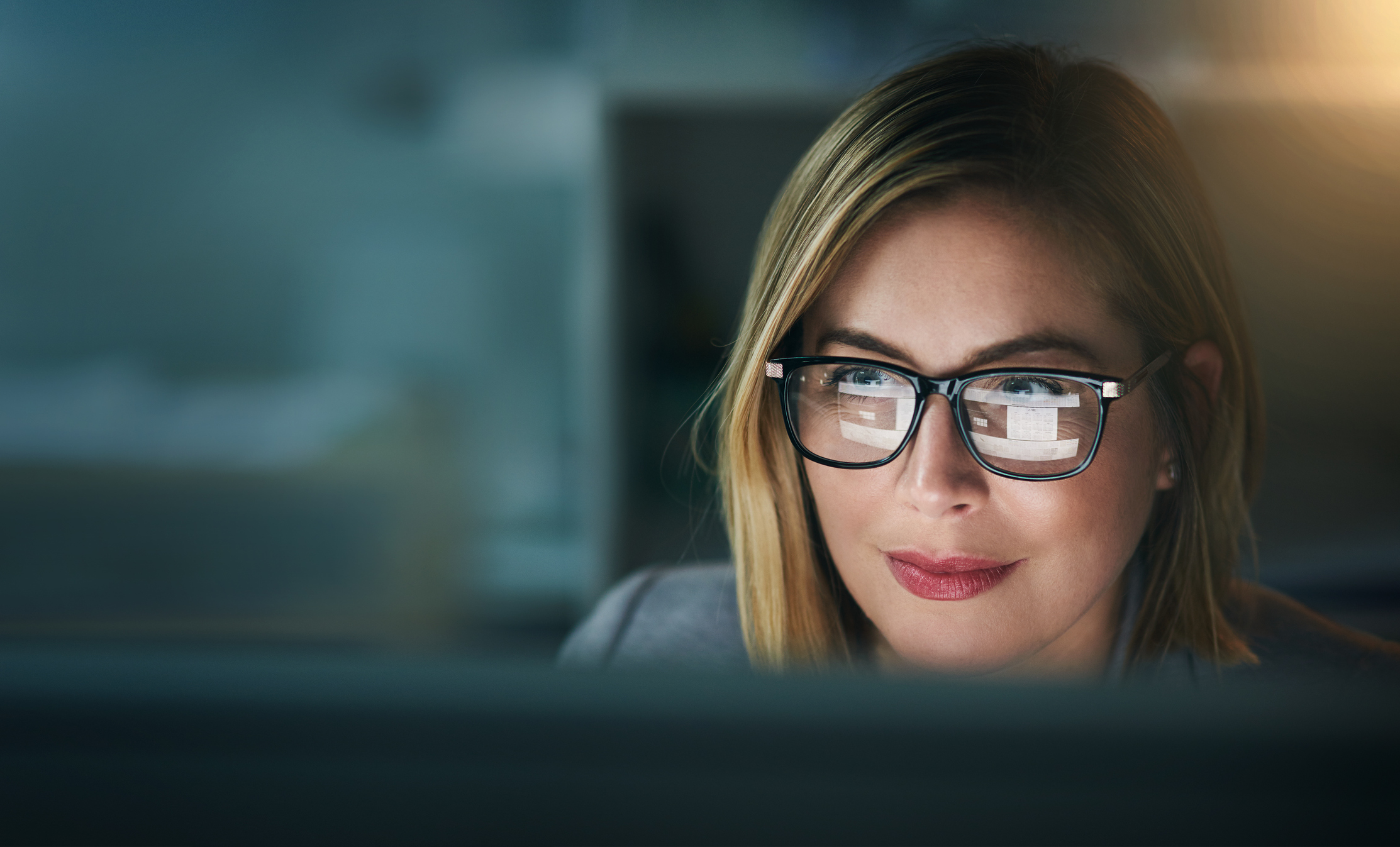 A woman in glasses looking at a computer screen