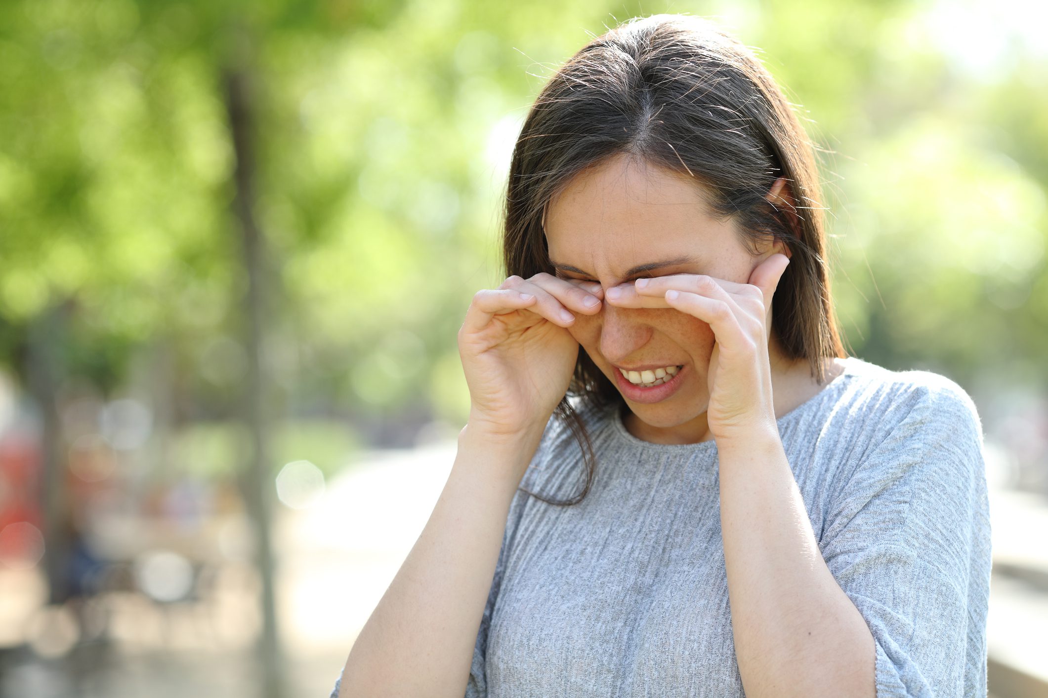 A woman rubbing her eyes outdoors