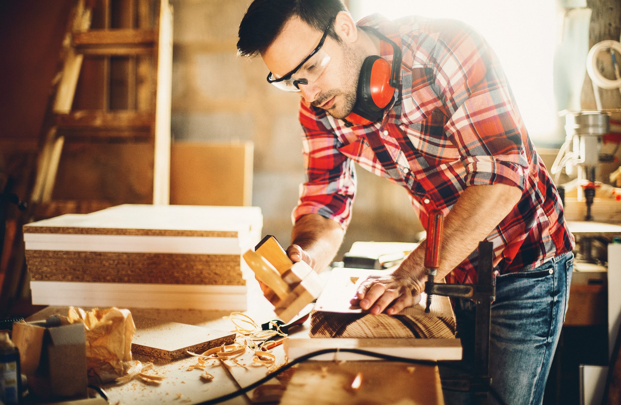 A man woodworking and sanding a long wooden board.