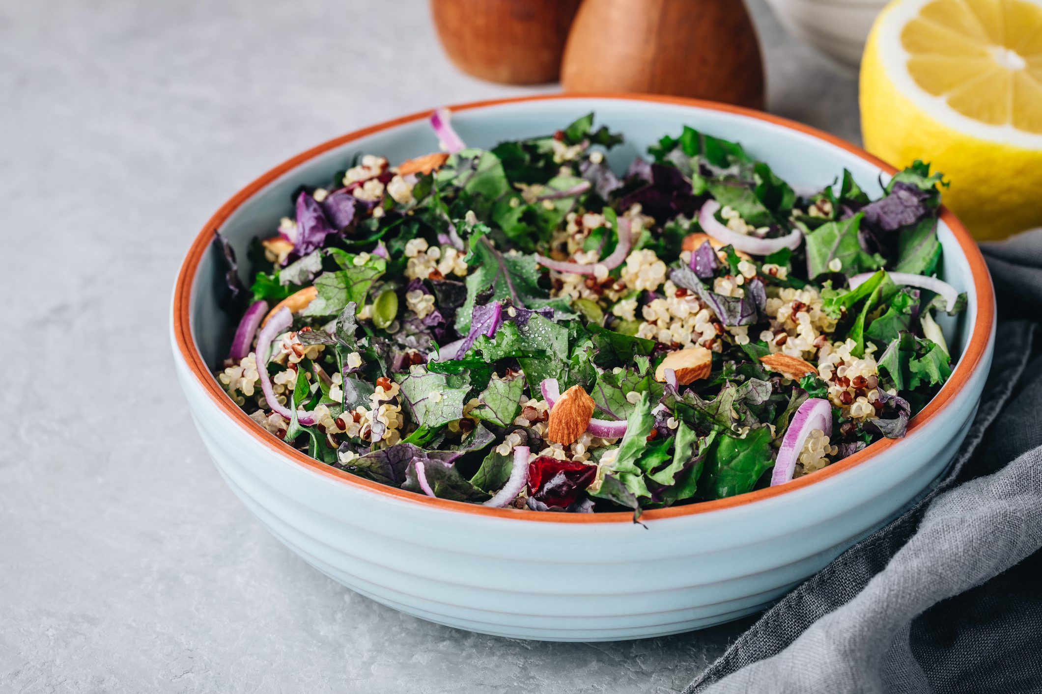 A bowl of salad with eggs and lemons sitting next to it.