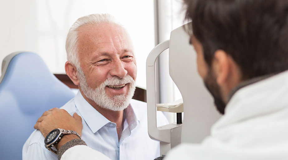 An older smiling man speaking with a doctor