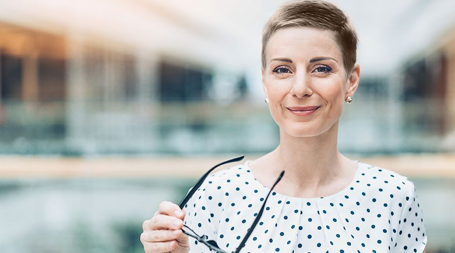 A smiling woman holding glasses