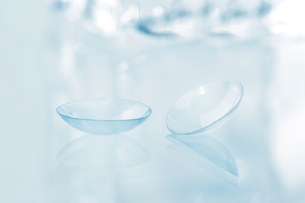 A closeup of a pair of contact lenses on a bright clear background.