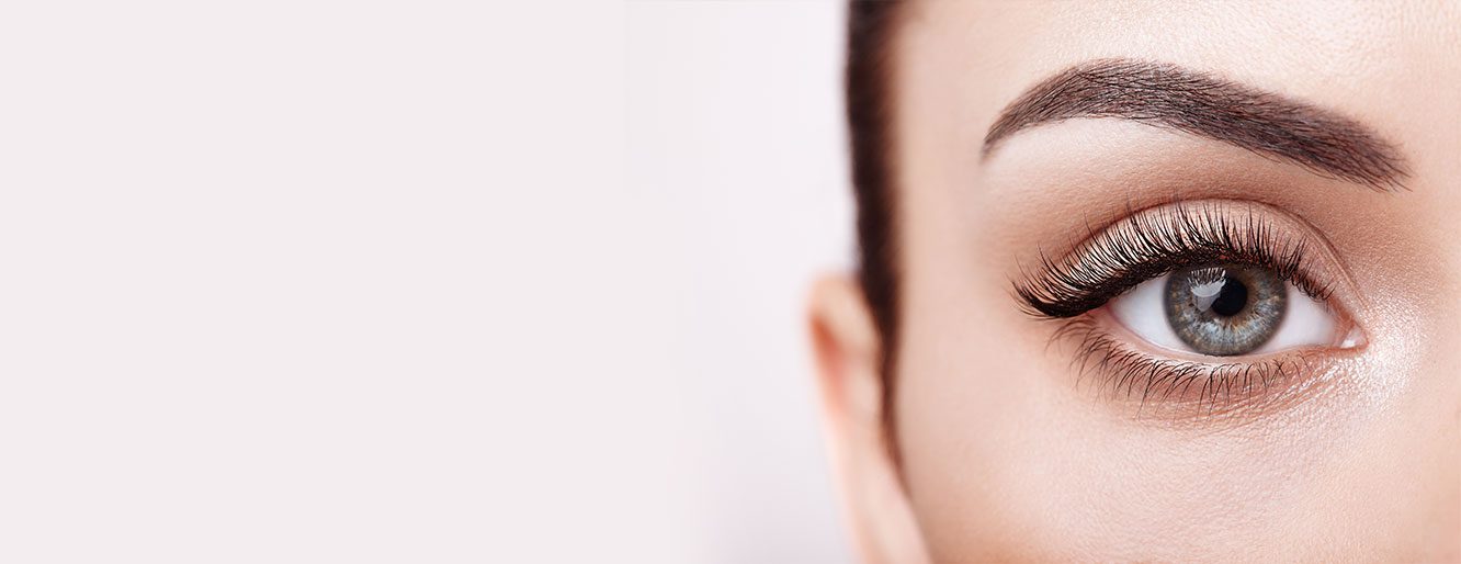 A closeup of a woman's gray eye and well-manicured eyebrow