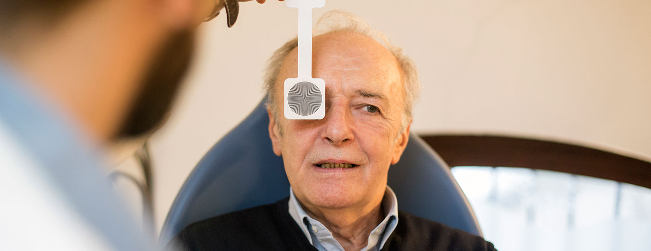 An older man receiving an eye exam on his right eye.