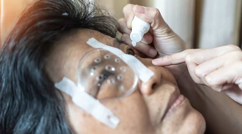 A doctor applying eye drops on a patient.