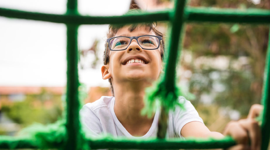 a smiling child in glasses playing on a playground