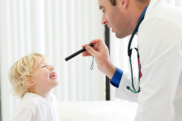 A laughing child having their eye's examined by a doctor.