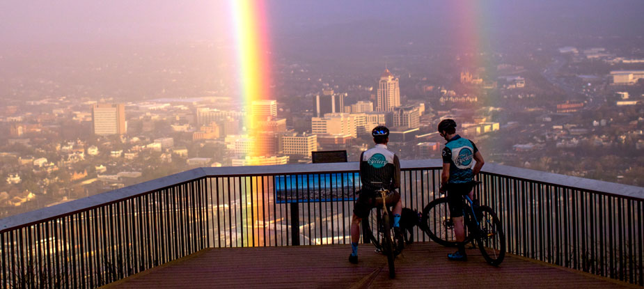 Two cyclists overlooking Roanoke, Virginia with a rainbow in view