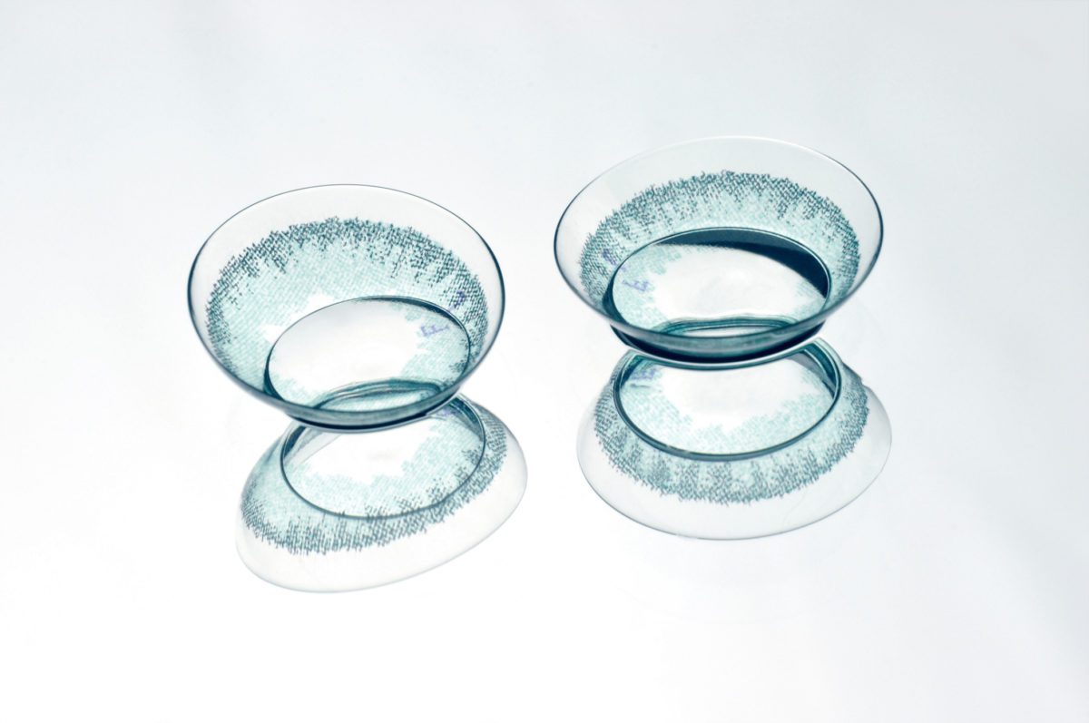 Pair of colored contact lenses on a gray background.