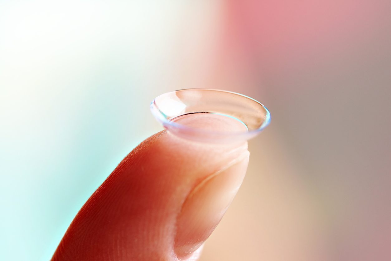 A closeup of a finger holding a contact lens.