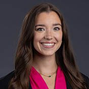 Headshot of a brunette woman smiling for the camera in front of a dark gray background